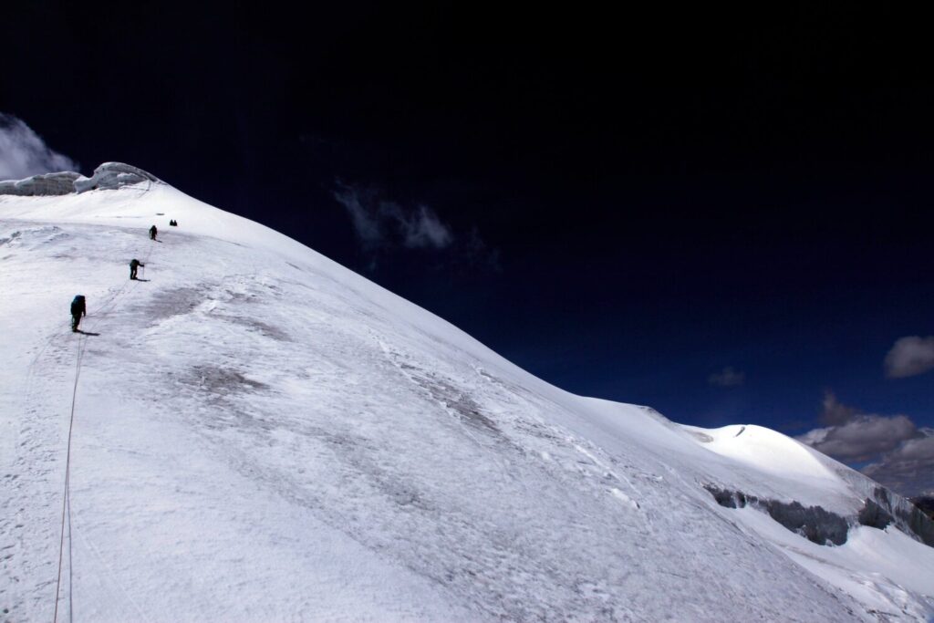 A group of climbers ascending the final snowfield as they approach the summit of Mentok II (6,150m), Mentok Group, Tso Mori region.