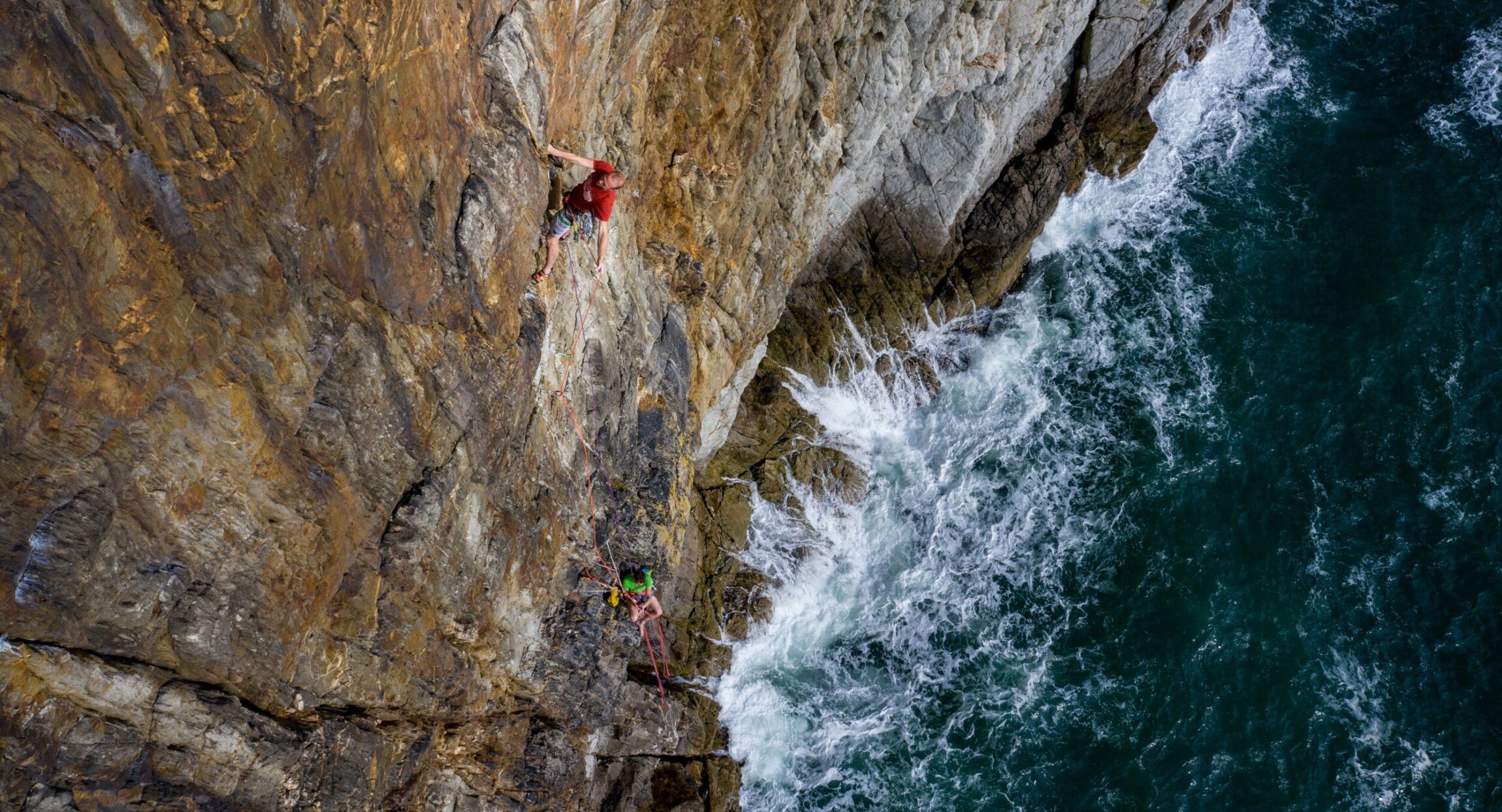 Alex Mason Powell on the Main pitch of Ramadam on Main cliff Gogarth, Dan Mcmanus belaying.