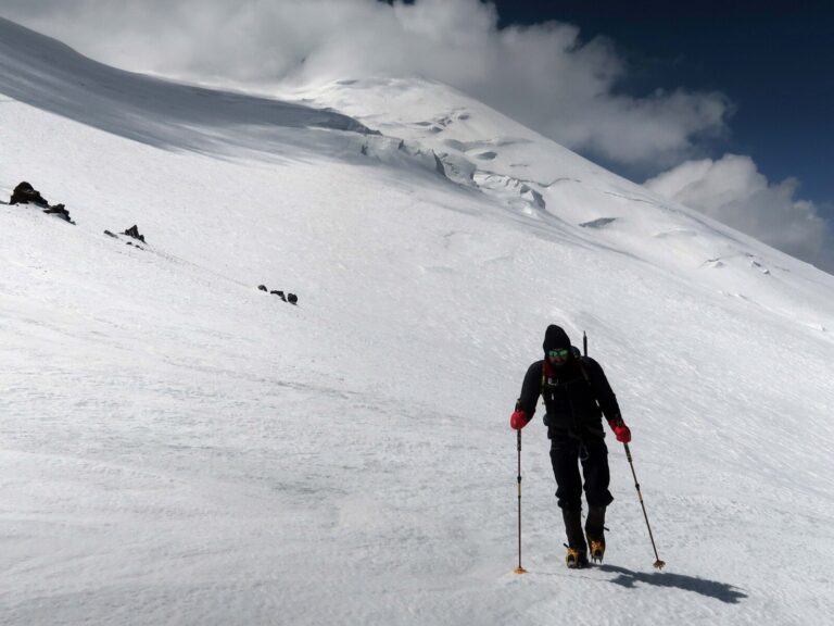 Pushing on towards the west summit of Elbrus (seen in the distance above the climber) after a break for refreshment at Lenz Rocks.