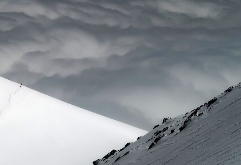 Two climbers dwarfed by the monumental scale of Elbrus as they descend towards the Maliou Azaou glacier on the south side. The southern route up the mountain is considerably easier than the northern route, since the summit push involves a much smaller altitude gain.