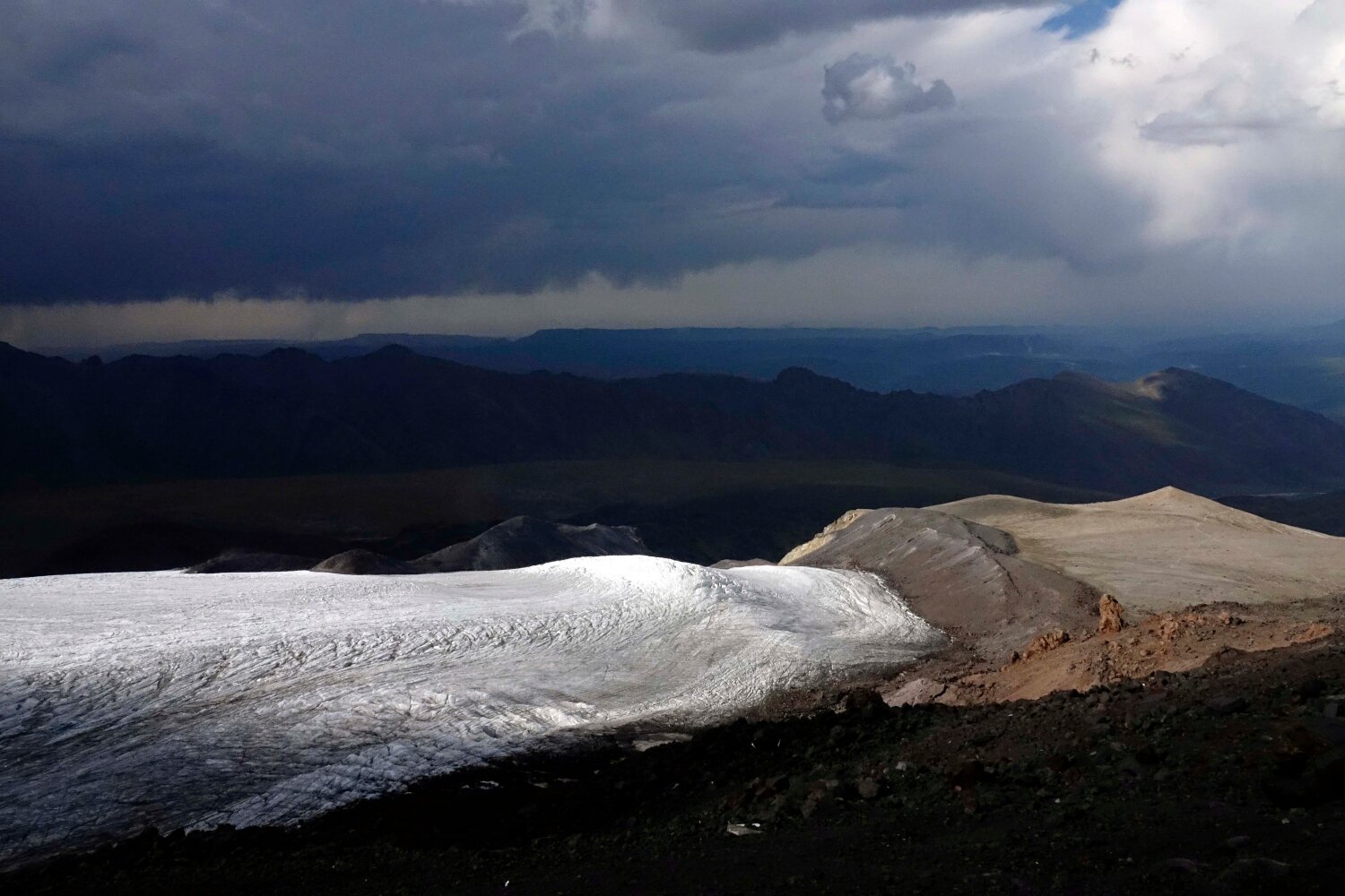 Looking down across Oulloulok glacier towards basecamp in stormy light from high camp at North Hut.