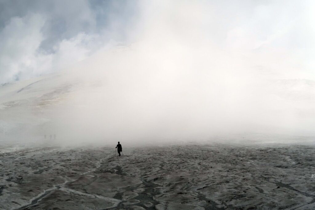 A climber descending in swirling cloud from an acclimatisation hike on the Bourbzalitchiran glacier above North Hut.