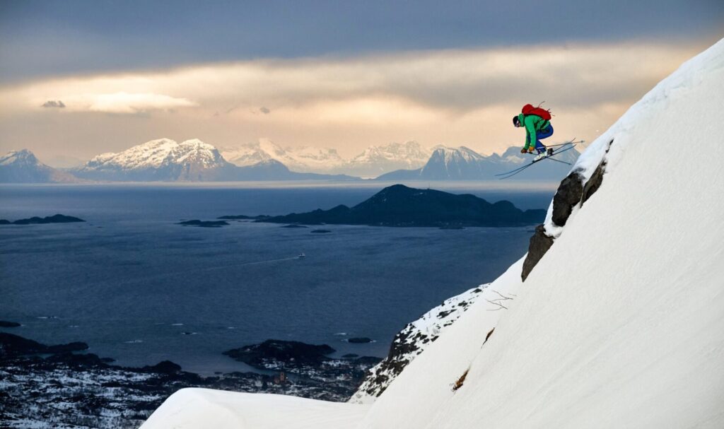 Fabian Linge taking some big air off a small rock outcrop with the awe-inspiring Lofoten Island skyline in the background. Skiing from summit-to-sea is a frequent possibility in Arctic Norway.